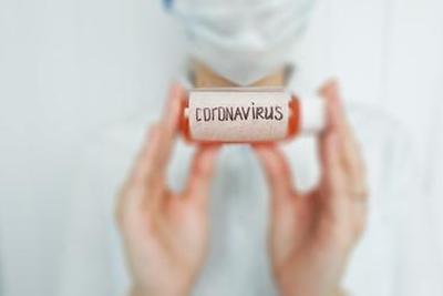 image of a person wearing a facemask holding a small bottle labeled 'coronavirus'
